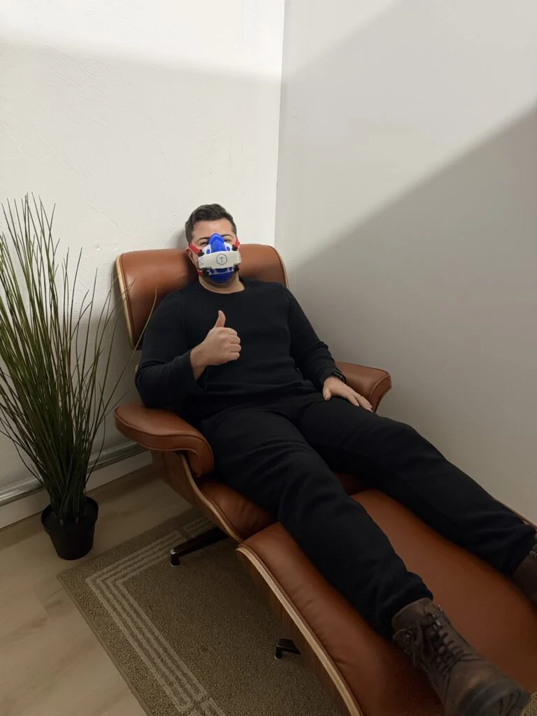 Client giving a thumbs-up in a leather recliner during a resting metabolic rate test