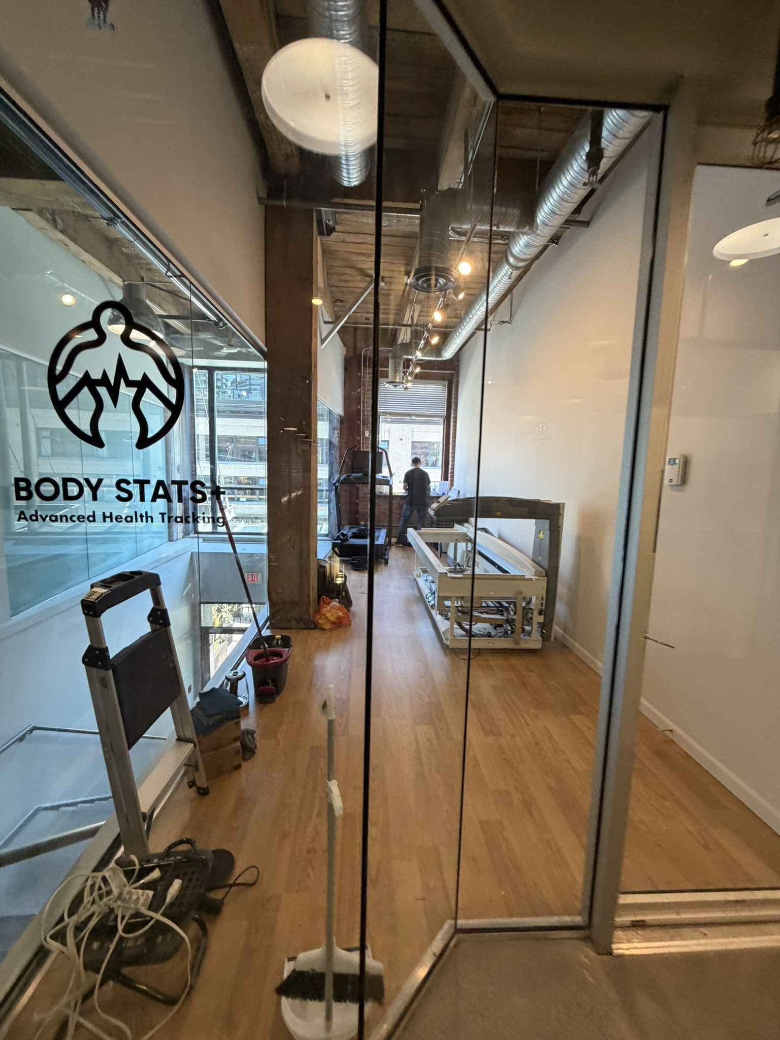 Frosted BodyStats logo on a glass partition with the DEXA scanner visible behind, Yaletown studio