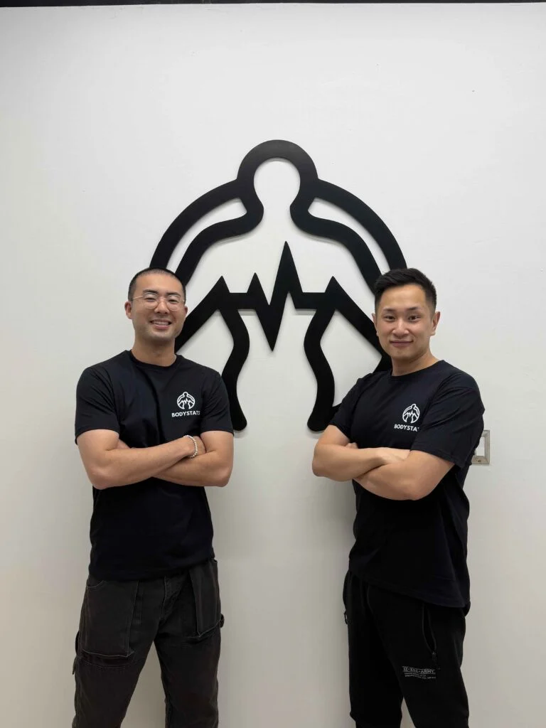 BodyStats team standing in front of the BodyStats logo wall