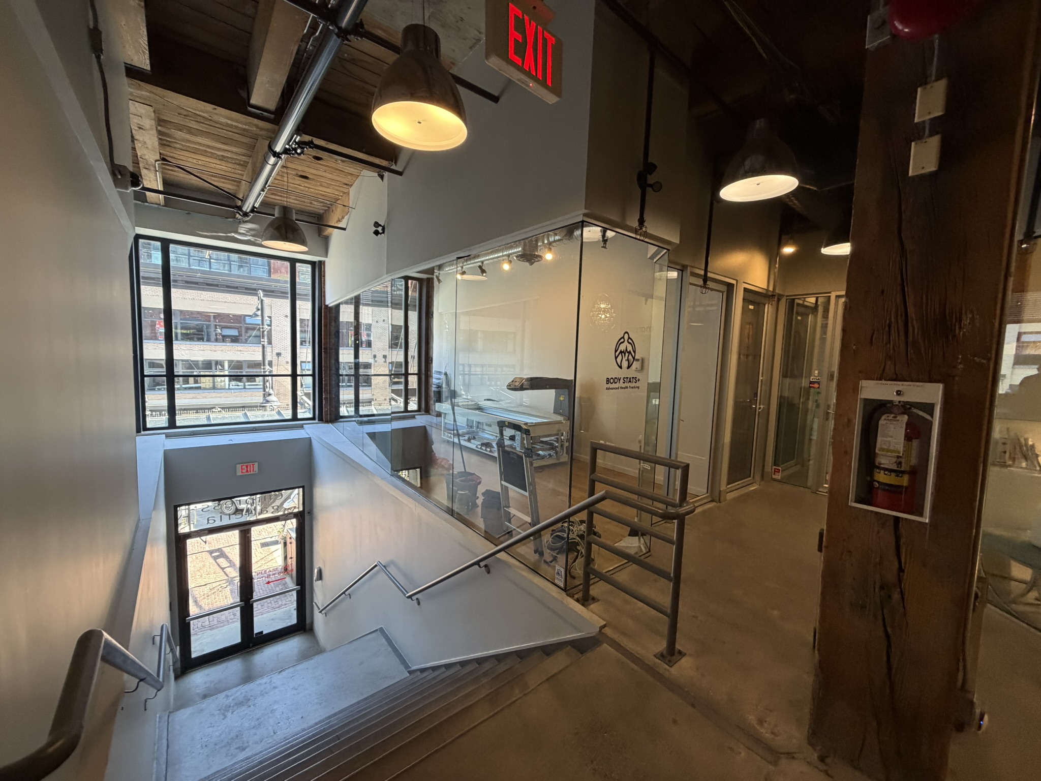BodyStats Yaletown studio overlook from the mezzanine stair with timber beams and downtown light