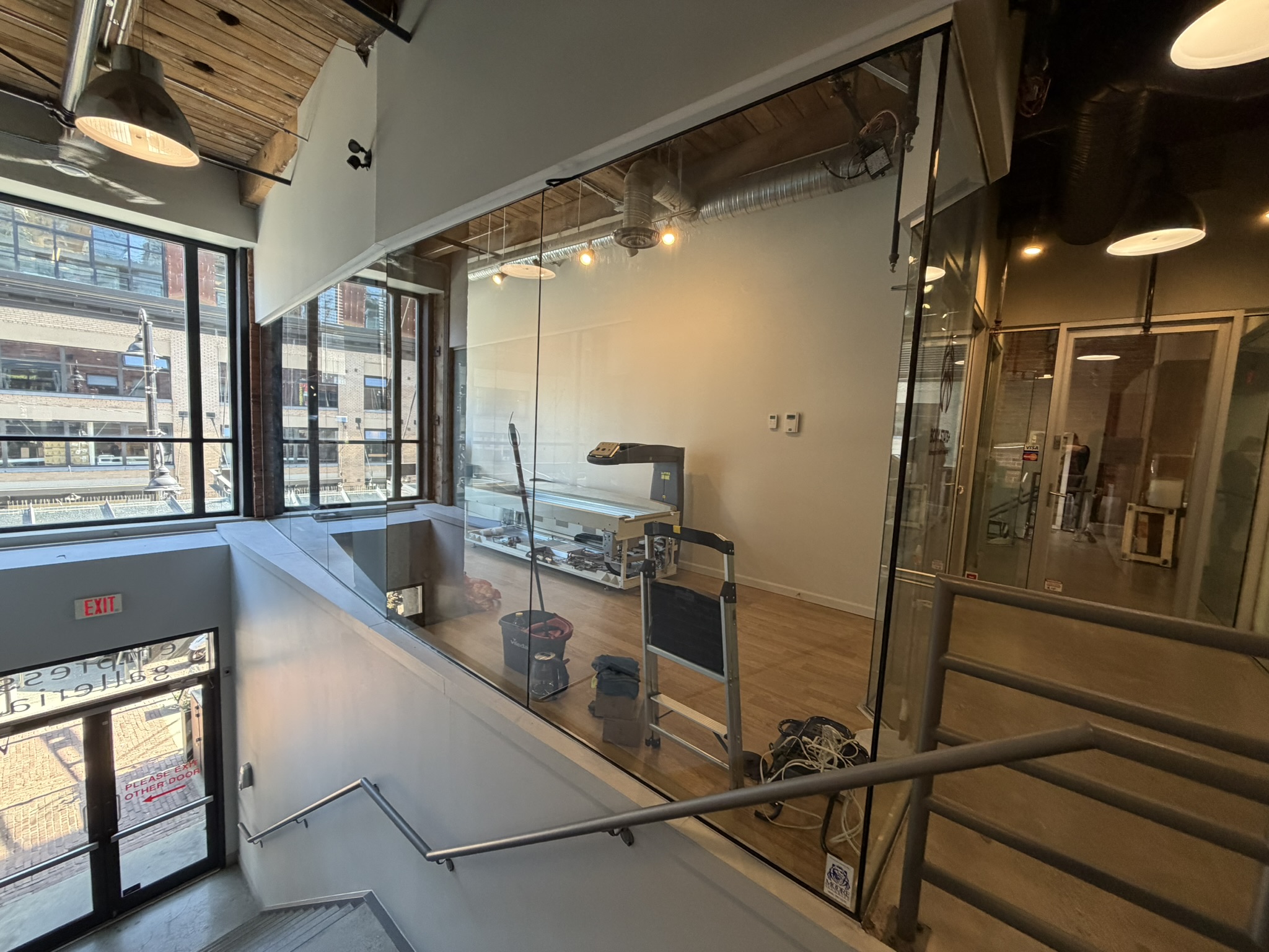 Mezzanine view through glass into the BodyStats Yaletown studio, with stairs and railings in foreground