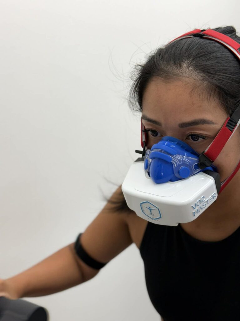 Woman performing a VO2 max test on a stationary bike with VO2 Master mask
